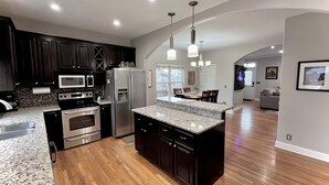 A modern kitchen with dark cabinetry, stainless steel appliances, and a granite countertop. - Enjoy a spacious private residence loaded with amenities. Minutes to everything! (Nashville)
