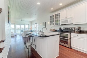 A modern kitchen with white cabinetry, a central island with a sink, and stainless steel appliances.