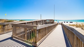 Una passerella in legno conduce a una spiaggia, con un cartello che indica l'area riservata ai passeggini.