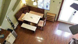 A compact living space with a dining table, bench seating, a small kitchenette, and a window with blinds.