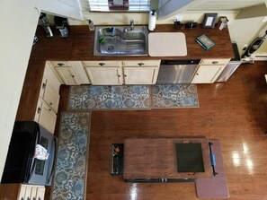 A kitchen with a stainless steel sink, wooden cabinets, a dishwasher, and a dining area with a table and chairs.