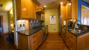 Una cocina con armarios de madera, encimeras de granito, estufa y refrigerador.