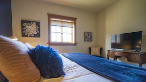 Un dormitorio con cama, cómoda, televisor y ventana.
