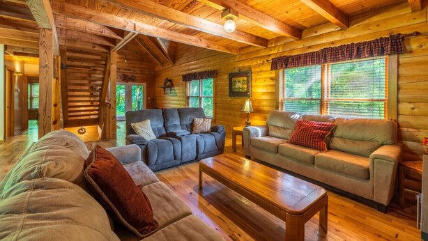 A log cabin interior with a wooden ceiling, two sofas, a bench, and a fireplace. - *Veteran Owned, Wi-Fi, pet friendly, playground (Lancaster)