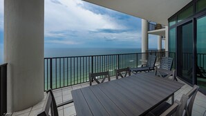 A balcony with a view of the ocean, a table, and chairs. - The Oasis at Orange Beach, formerly known as Phoenix West II, Unit 2509 (Orange Beach)