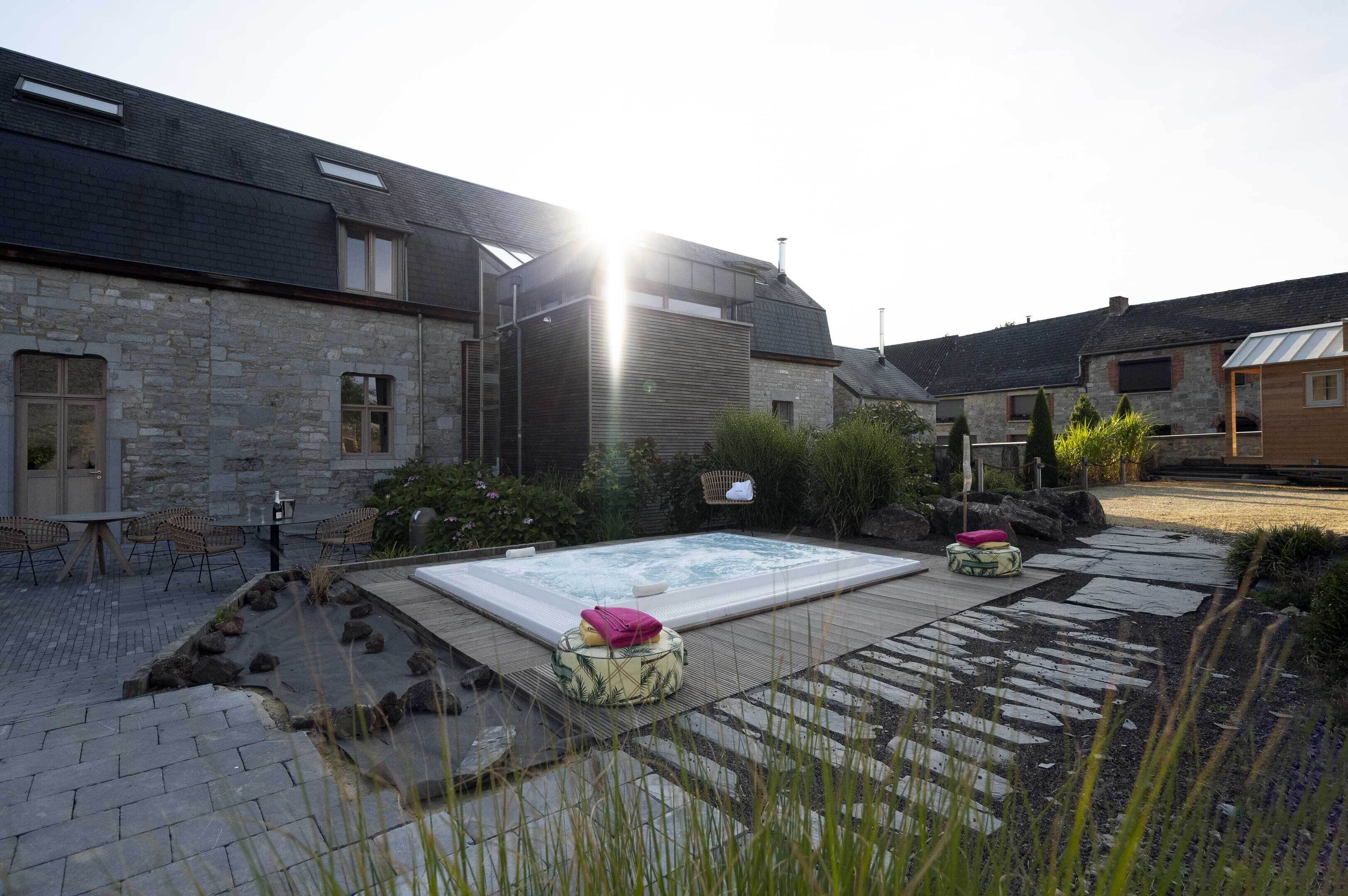 A spa area with a hot tub, stone seating, and a stone wall.