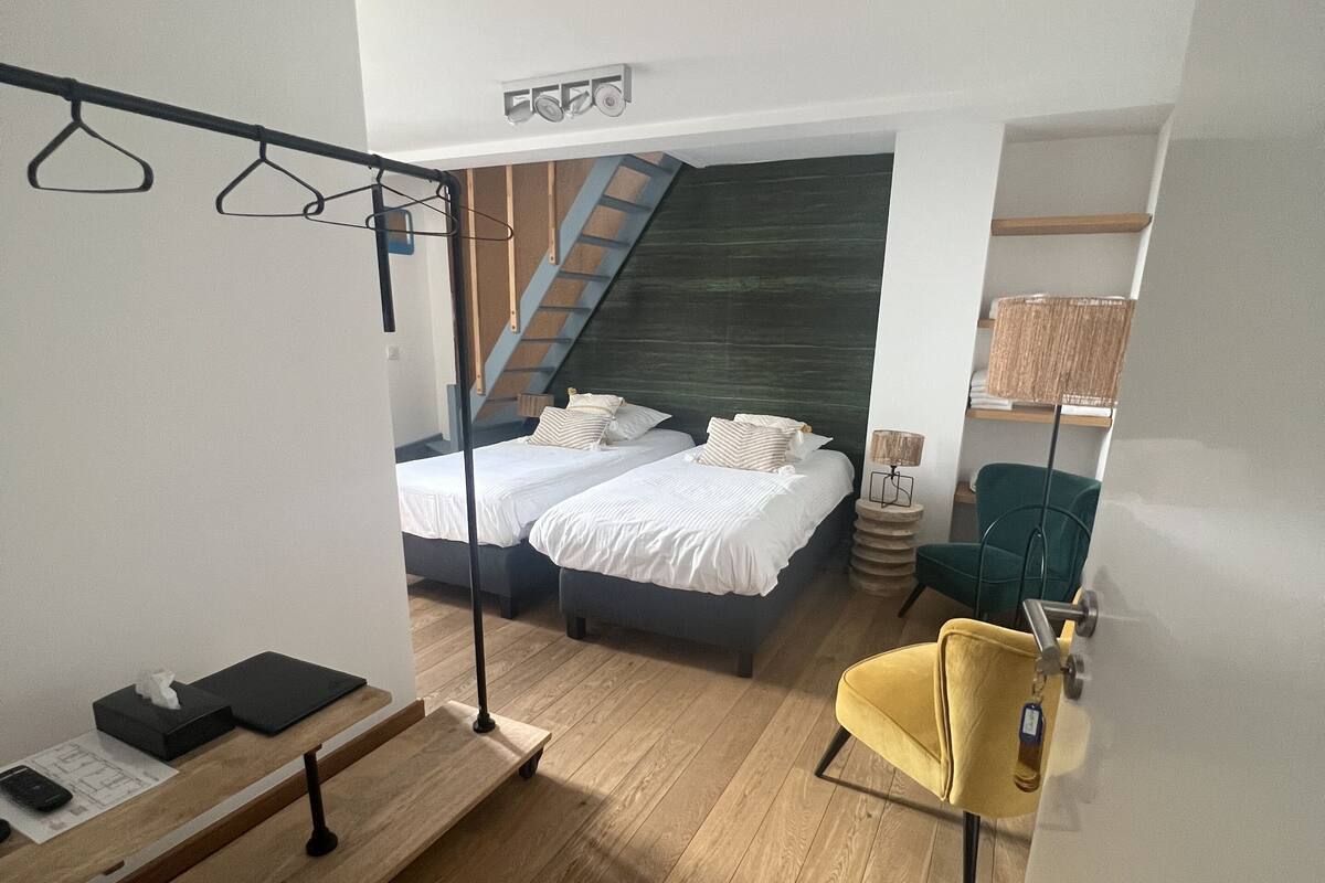Une chambre à coucher moderne avec un lit, un banc, une chaise et un escalier.