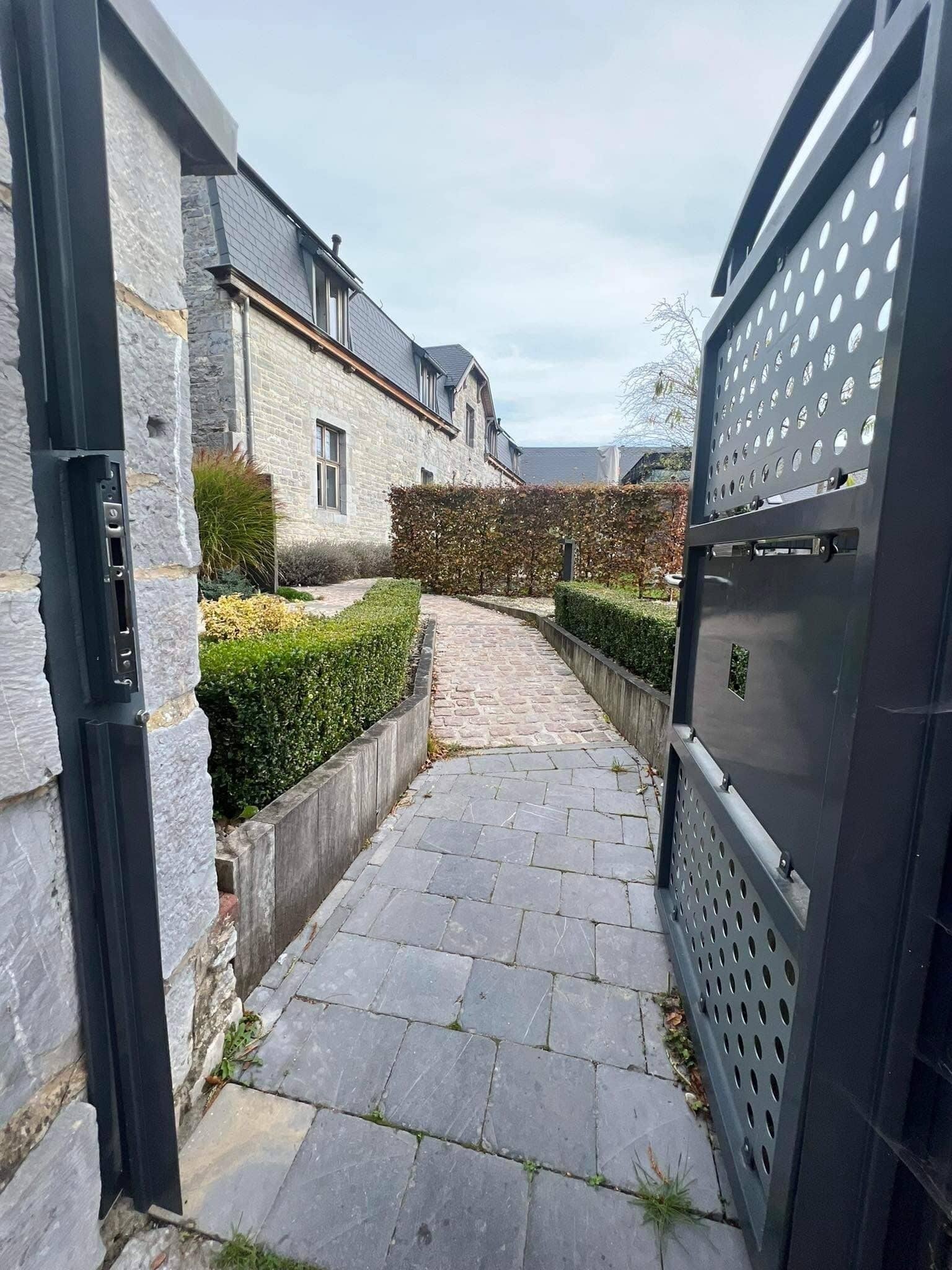 Een pad van stenen dat naar een huis met een metalen hek leidt.