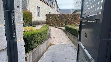 Een pad van stenen dat naar een huis met een metalen hek leidt.