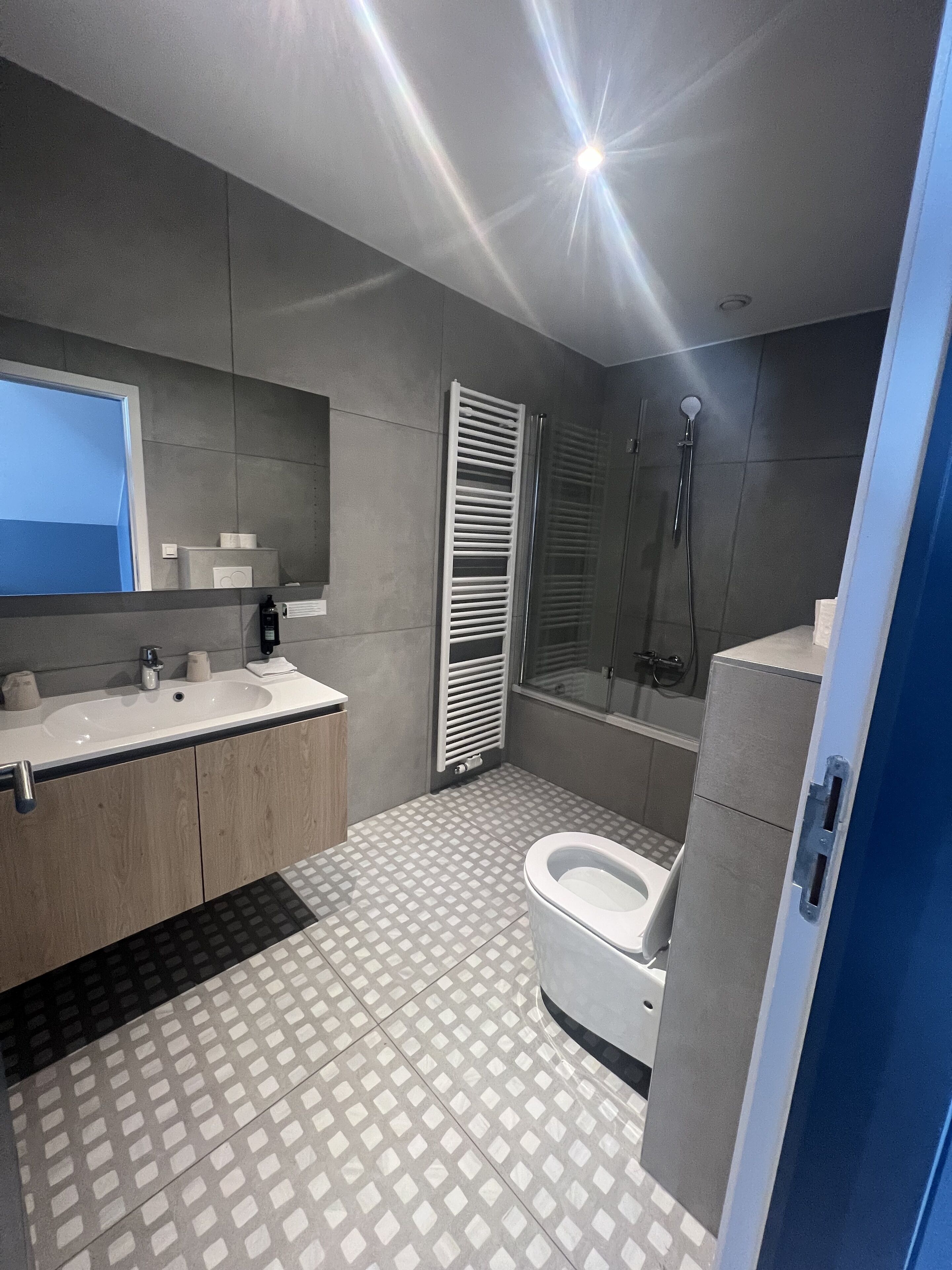 Un bagno moderno con uno specchio grande, un lavandino, un water e una doccia.