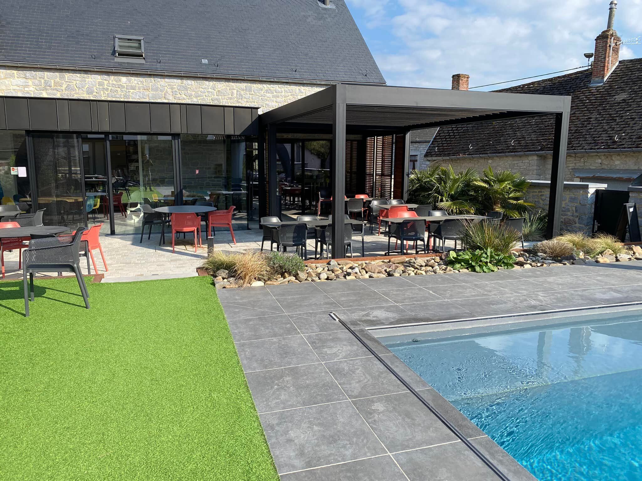 A modern outdoor patio with a pool, stone walls, and a covered seating area.