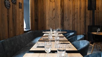 A restaurant with wooden walls, black leather booths, and tables set with glasses and menus.