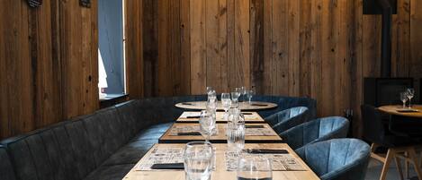 A restaurant with wooden walls, black leather booths, and tables set with glasses and menus.