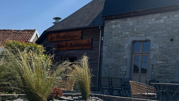 Un bâtiment en pierre avec une enseigne en bois, un chemin en pierre et un espace dédié à un bain à remous.
