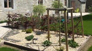 Un bâtiment en pierre doté de nombreuses fenêtres et d’un espace jardin avec une balançoire en bois.