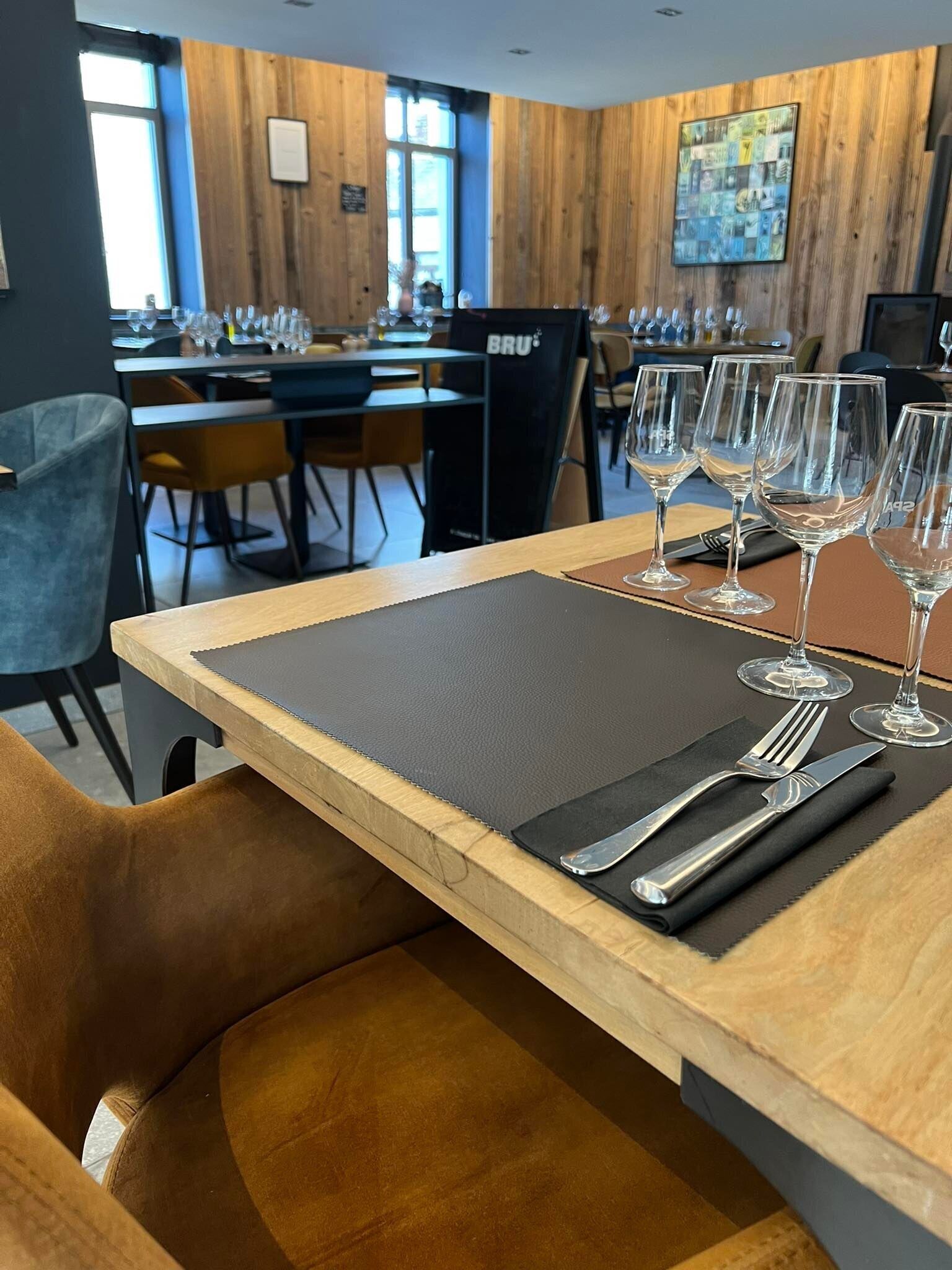 A dining area with a wooden table, black placemat, and wine glasses.