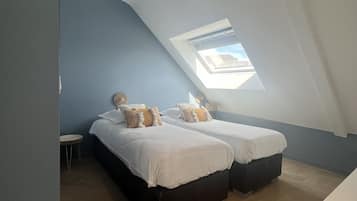 A room with two beds, a skylight, and a small table.