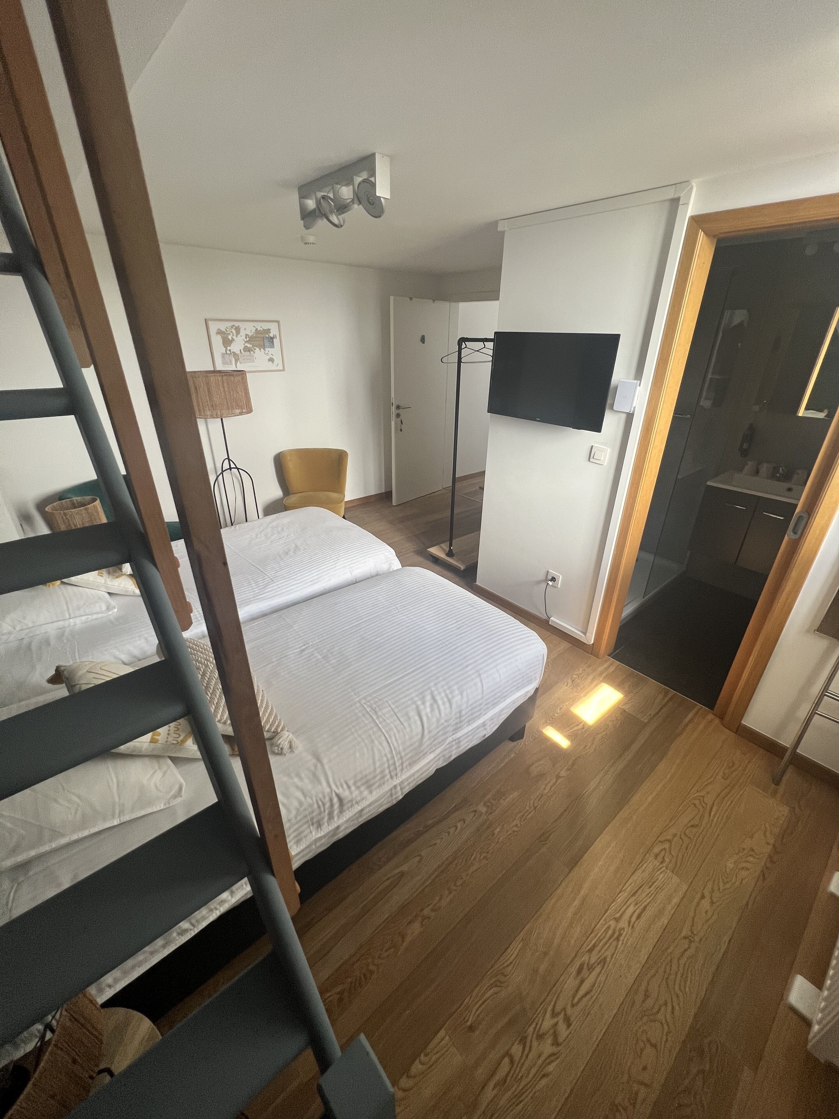 Un dormitorio con cama, una silla, un televisor y un armario.