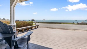 Una terraza de madera con vista al océano y afloramientos rocosos.