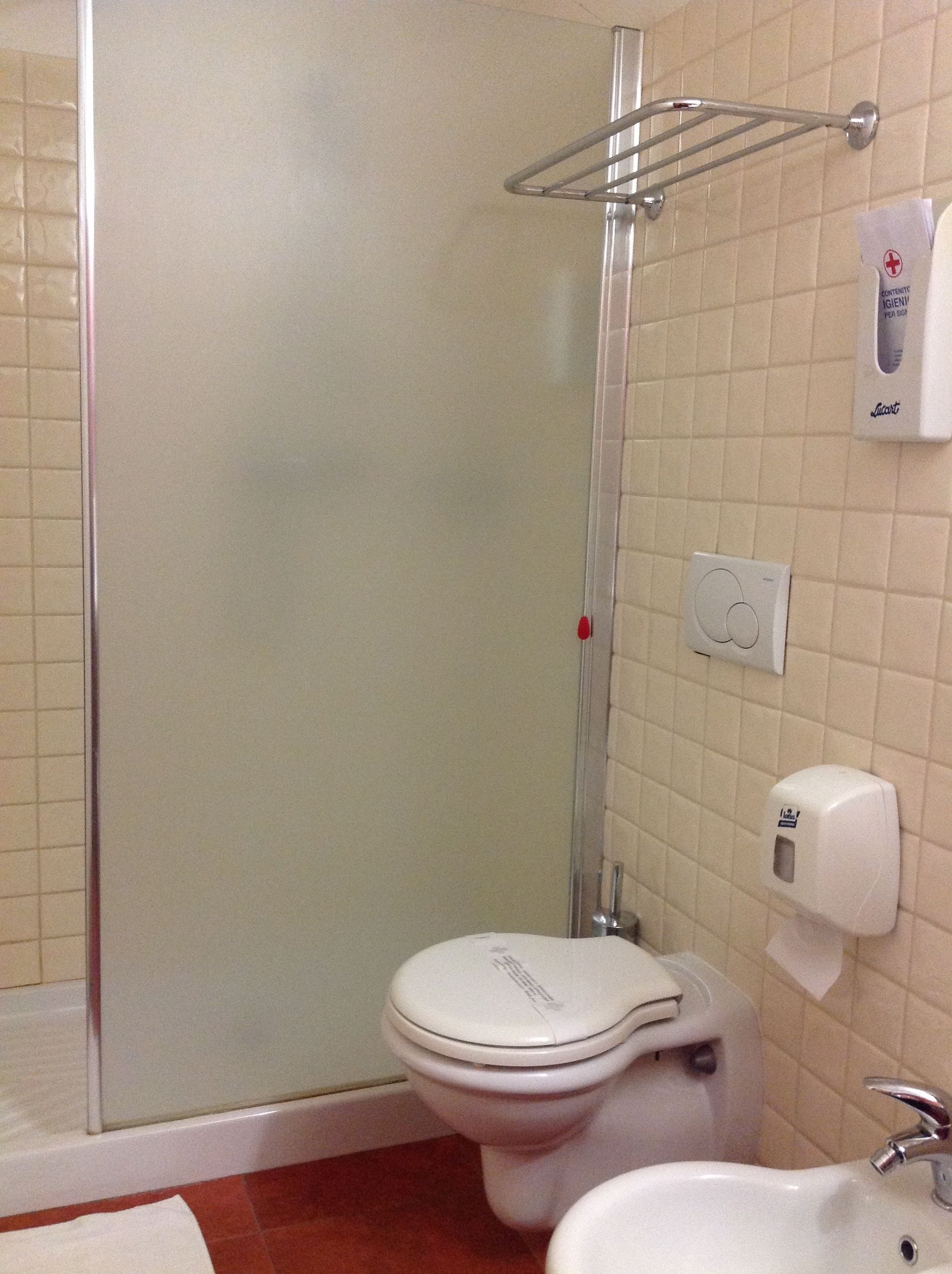 Ein Badezimmer mit einer Duschkabine, einer Toilette, einem Waschbecken und einem Handtrockner.