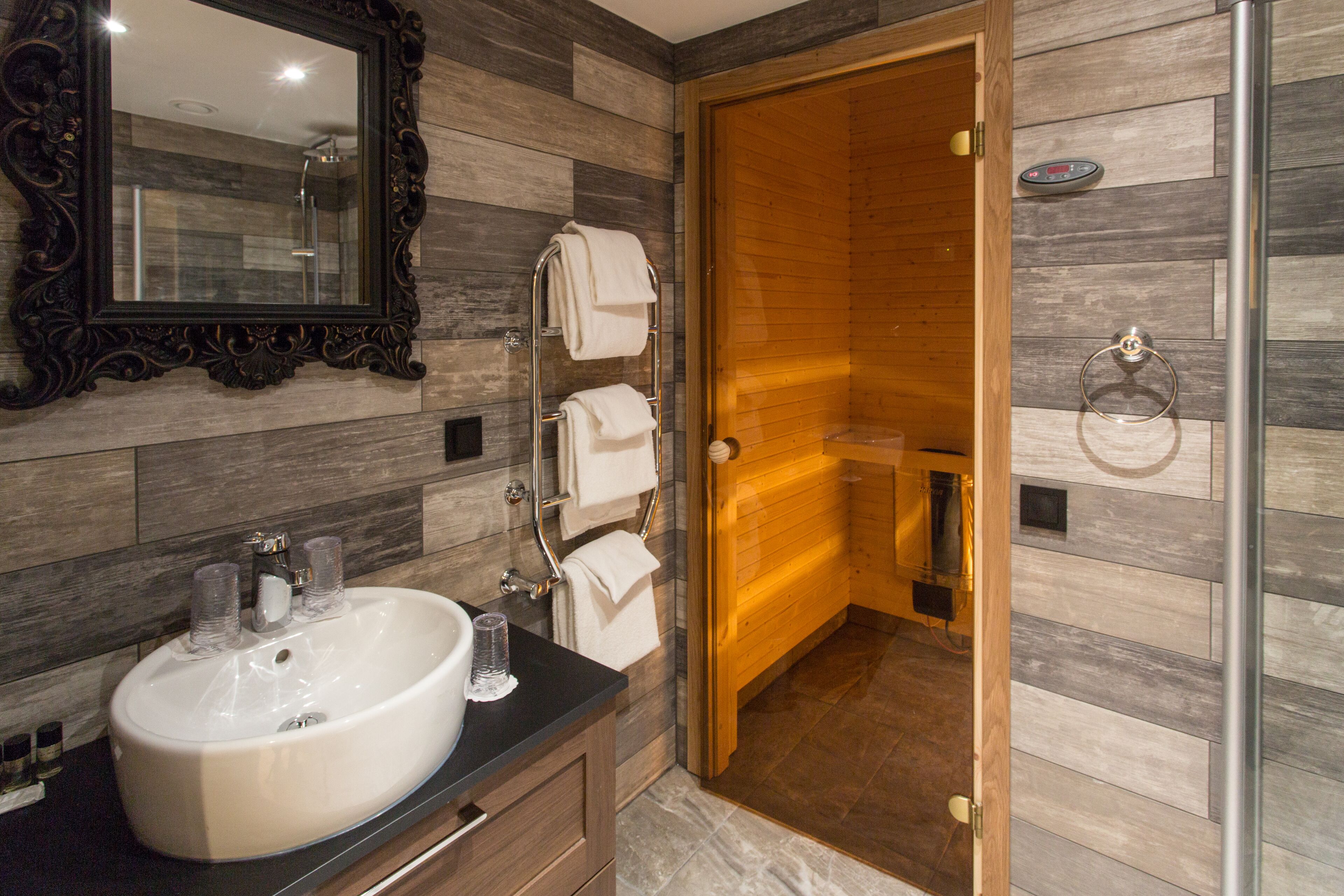 Une salle de bain avec un grand miroir, un lavabo avec deux verres et un porte-serviettes avec des serviettes.