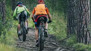 Two mountain bikers on a dirt trail in a forested area.