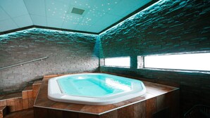 A spa area with a hot tub, wooden flooring, and brick walls. - Hotell Hallstaberget (Solleftea)