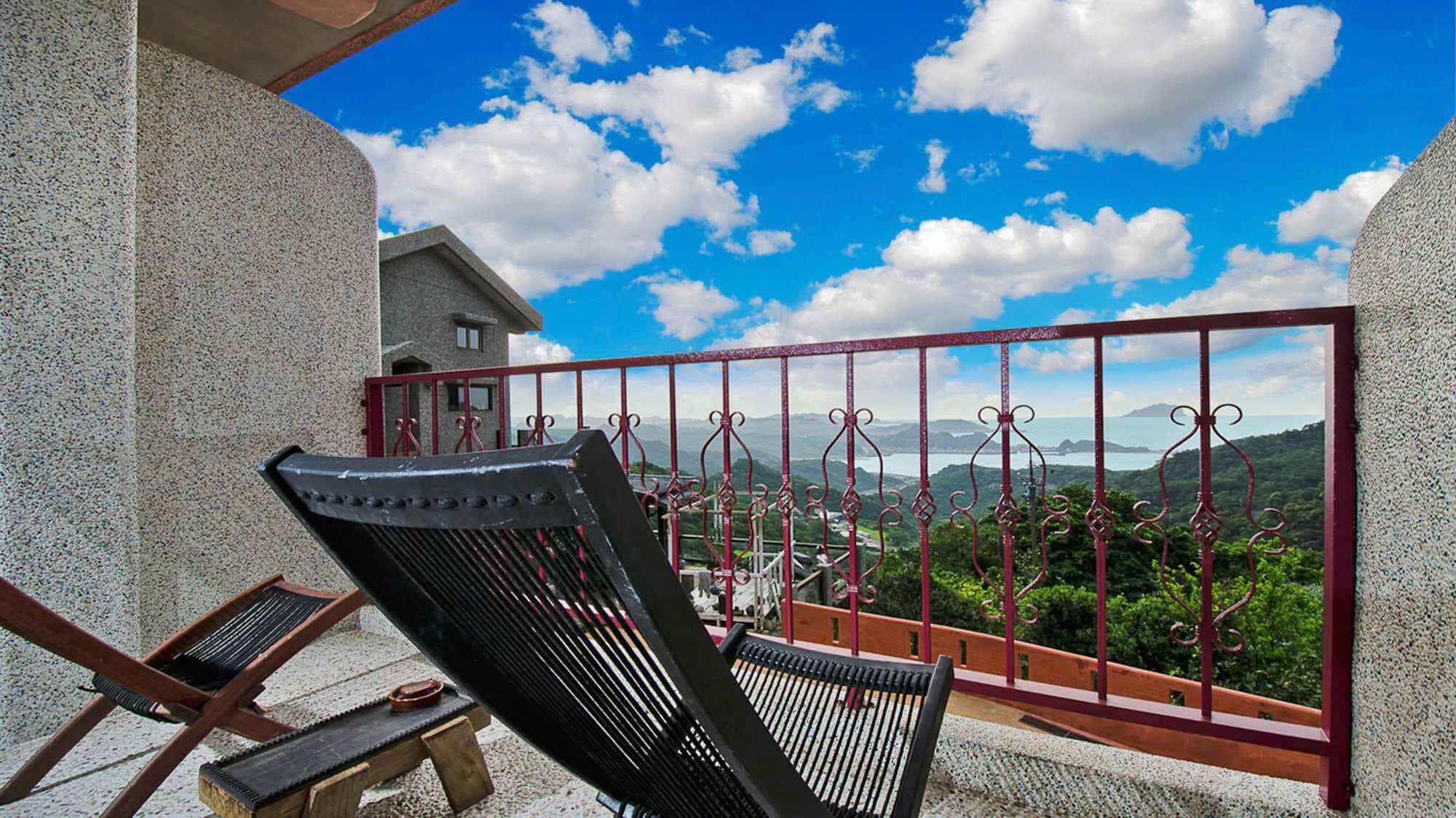 A balcony with a metal railing, a chair, and a table.