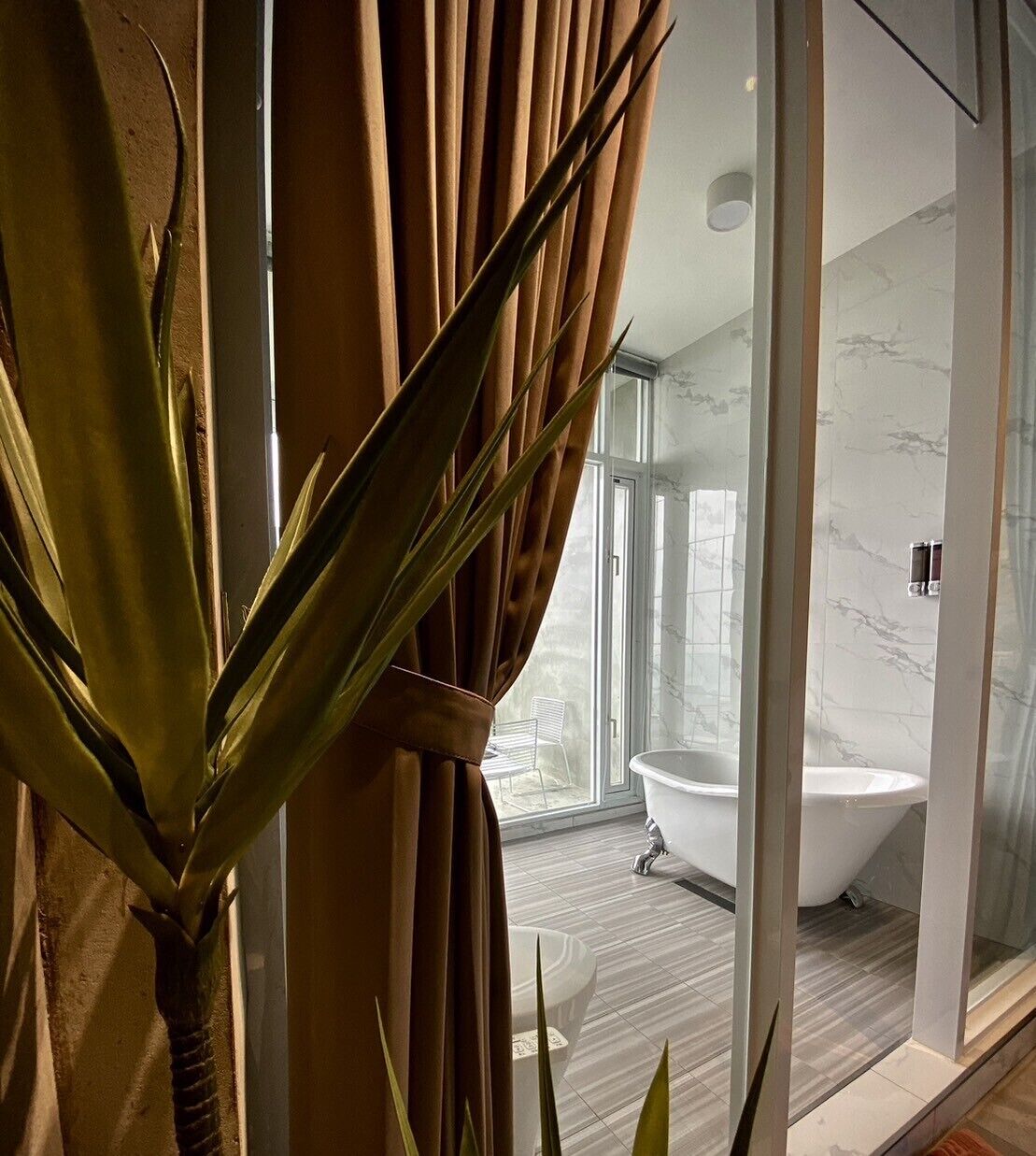 A modern bathroom with a freestanding bathtub, a glass shower enclosure, and a large window providing natural light.