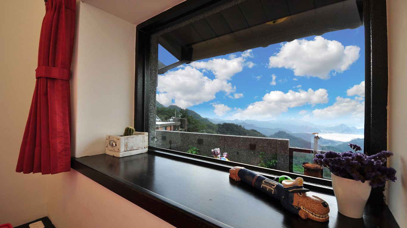 A window with a view of a mountainous landscape, a toy giraffe, a cactus, and a potted plant.