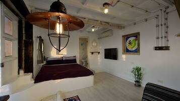 Un dormitorio moderno con una cama grande, una lámpara colgante, un televisor y un cuadro en la pared.