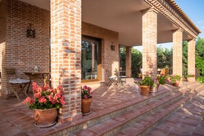 A covered patio with brick columns, outdoor seating, and potted plants. - B&B Villa Marín Toledo (Nambroca)