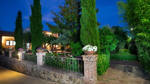 Un jardin bien entretenu, avec un mur de pierres, de grands arbres et des plantes en pot.