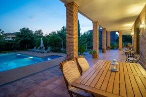 A covered patio area with a pool, lounge chairs, and a table with a lantern. - B&B Villa Marín Toledo (Nambroca)