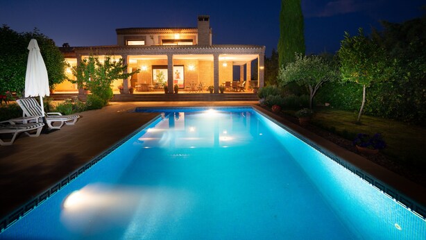 Une maison moderne dotée d’une piscine, de mobilier d’extérieur et d’un patio bien éclairé.