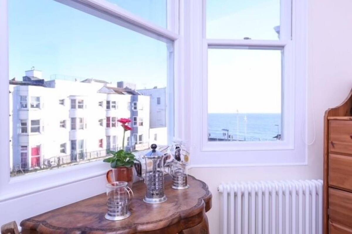 Une pièce avec vue sur les bâtiments et la mer, grâce à de grandes fenêtres.