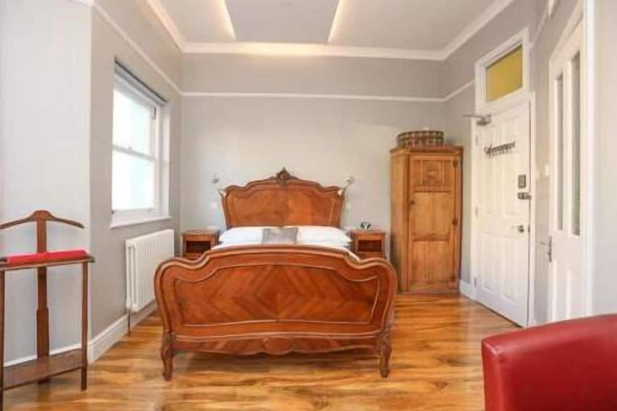 Une chambre à coucher avec un lit en bois, une table de chevet, une armoire et un radiateur.