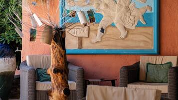 A cozy outdoor seating area with wicker furniture and a large mural on the wall.