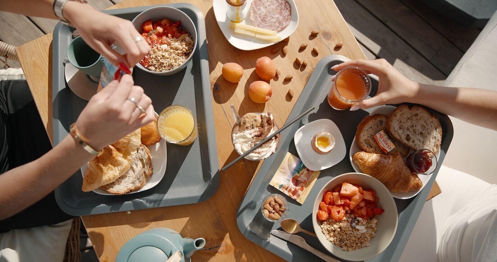 Un plateau de petit-déjeuner contenant divers aliments, notamment du pain, des œufs et des fruits.