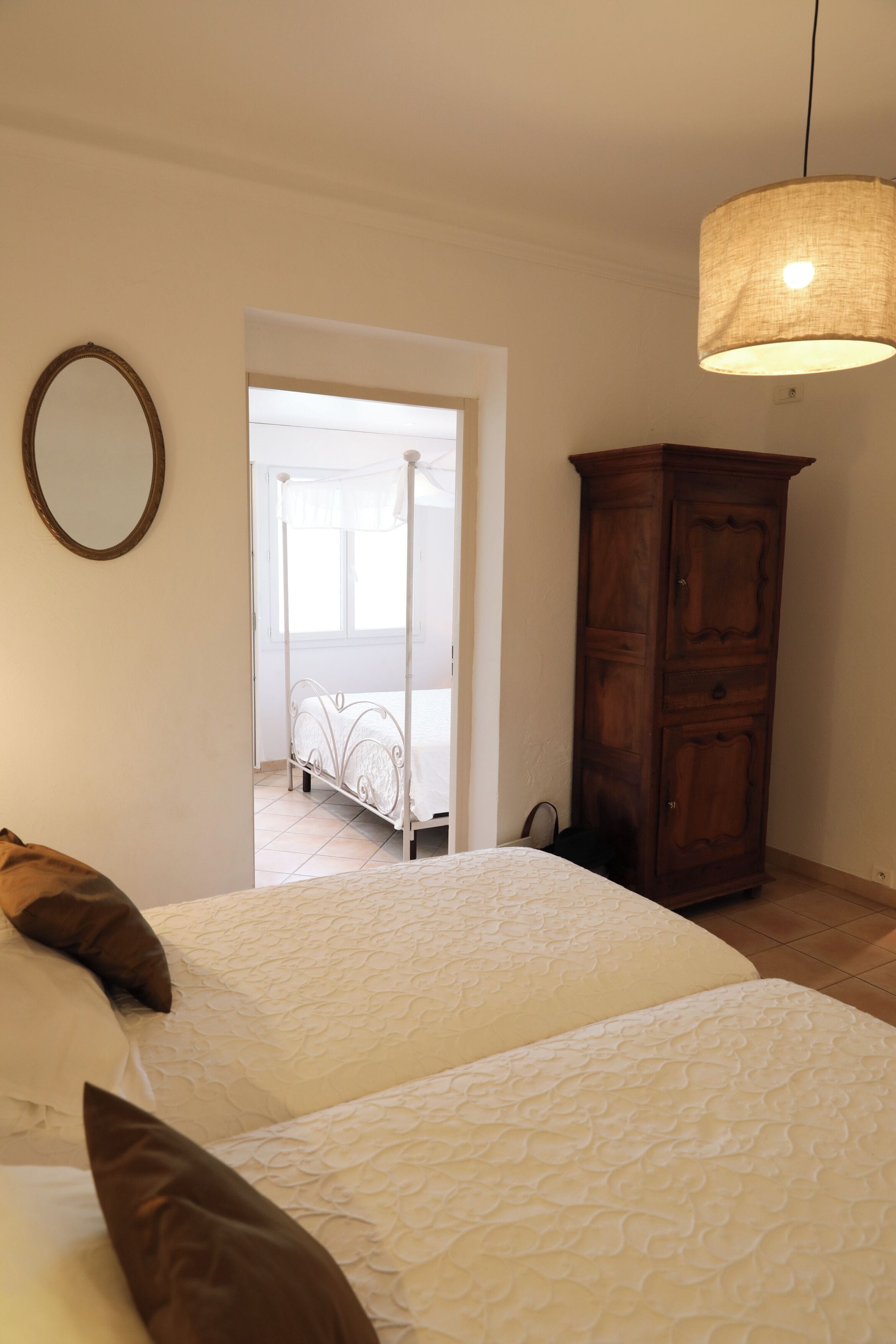 Une chambre à coucher avec un lit à baldaquin, une armoire en bois et un luminaire suspendu.