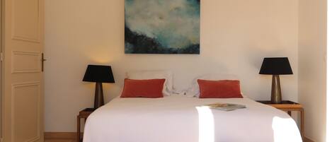 Habitación de hotel con una cama grande, dos mesitas de noche, un cuadro en la pared y una alfombra estampada.