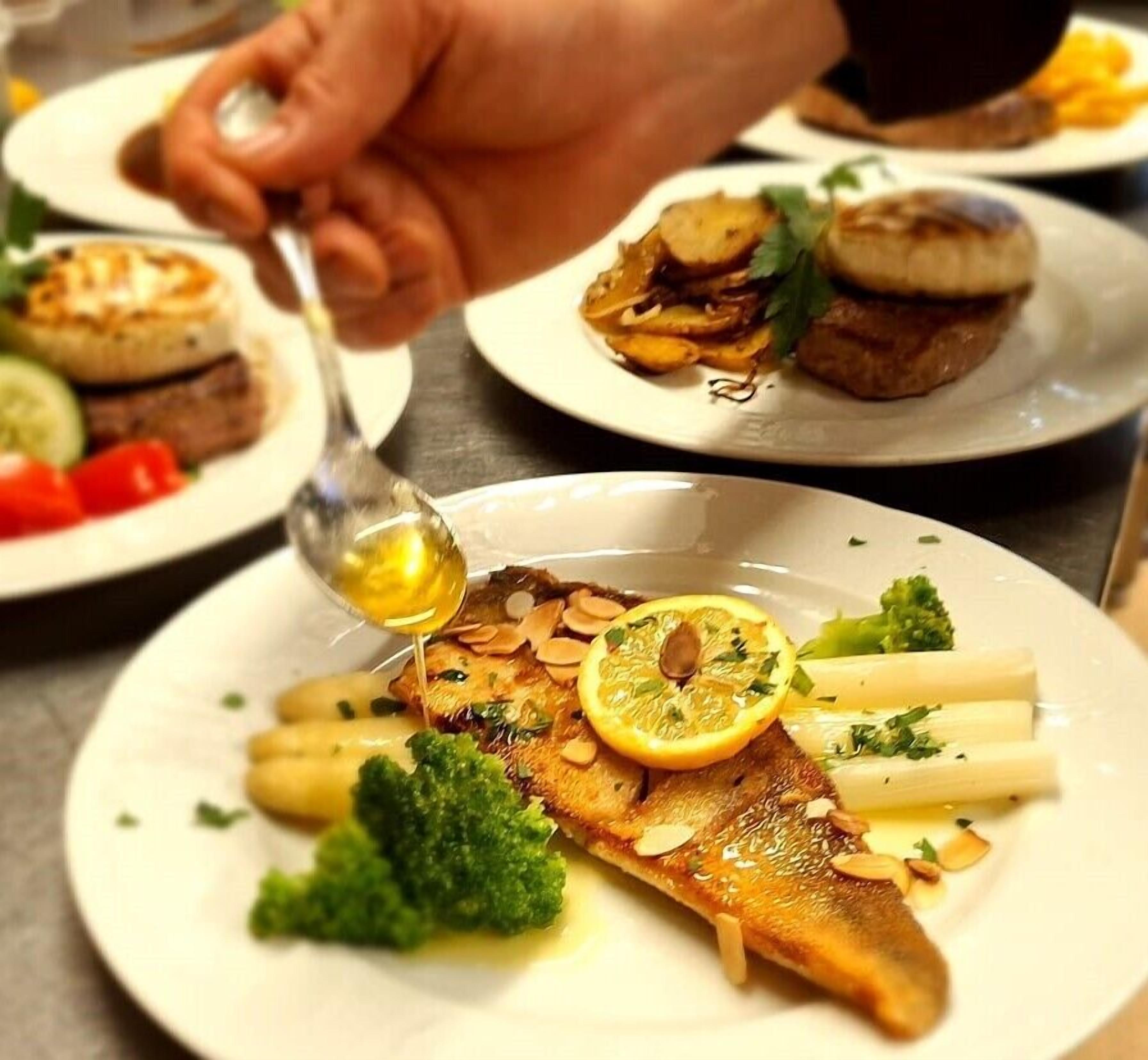 A plate with a fish, lemon, and vegetables.