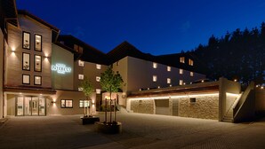 A hotel with a modern design, featuring a well-lit entrance, multiple windows, and a landscaped courtyard. -  Interest Vitalhotel (Oberstaufen)