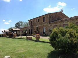 A stone building with a courtyard, large potted plants, and a well-maintained lawn.