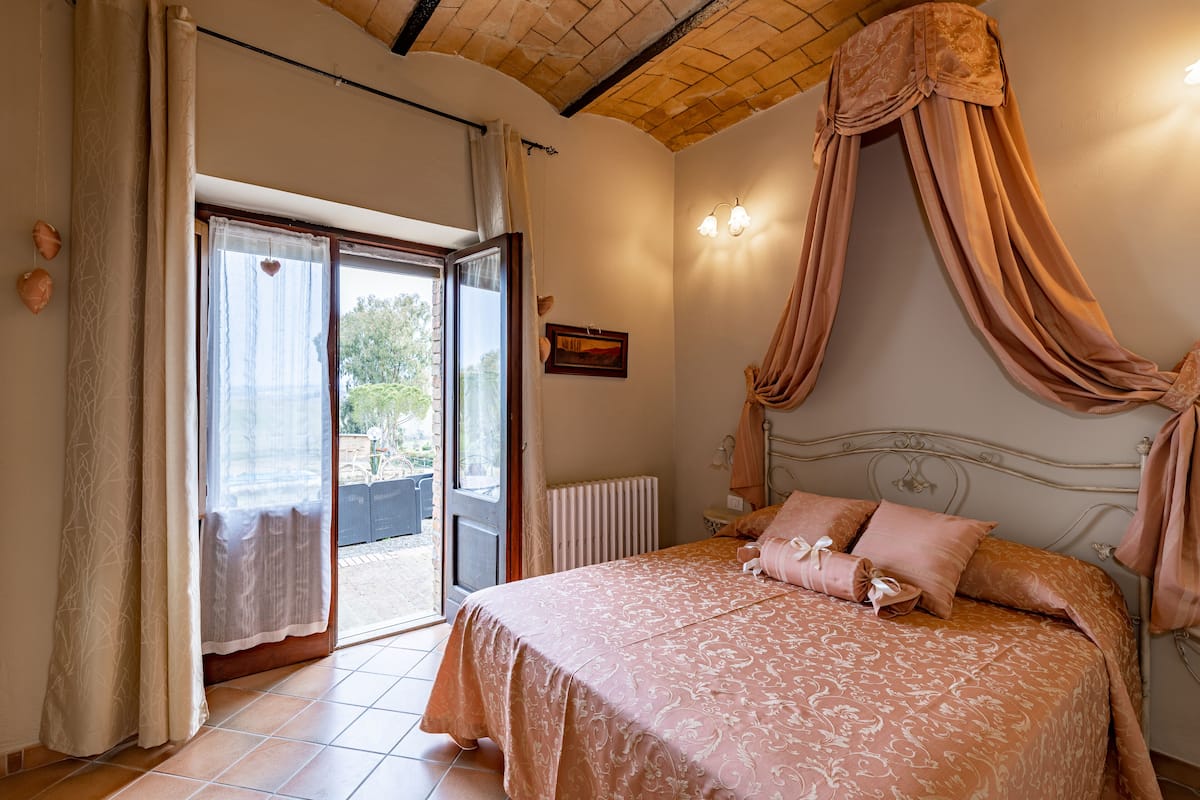 Une chambre à coucher avec un lit, des rideaux, une fenêtre et un radiateur.