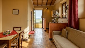 A cozy interior with a dining area, a sofa, and a kitchen. - Wine Resort Colsereno (Montalcino)