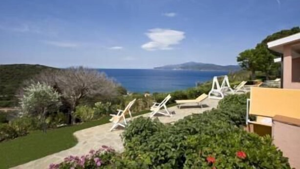 A coastal view with a garden and lounge chairs. - Appartamenti Casa Serena (Capoliveri)