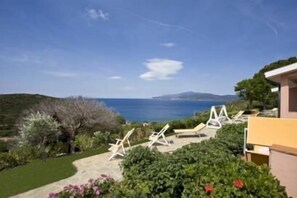 A coastal view with a garden and lounge chairs. - Appartamenti Casa Serena (Capoliveri)