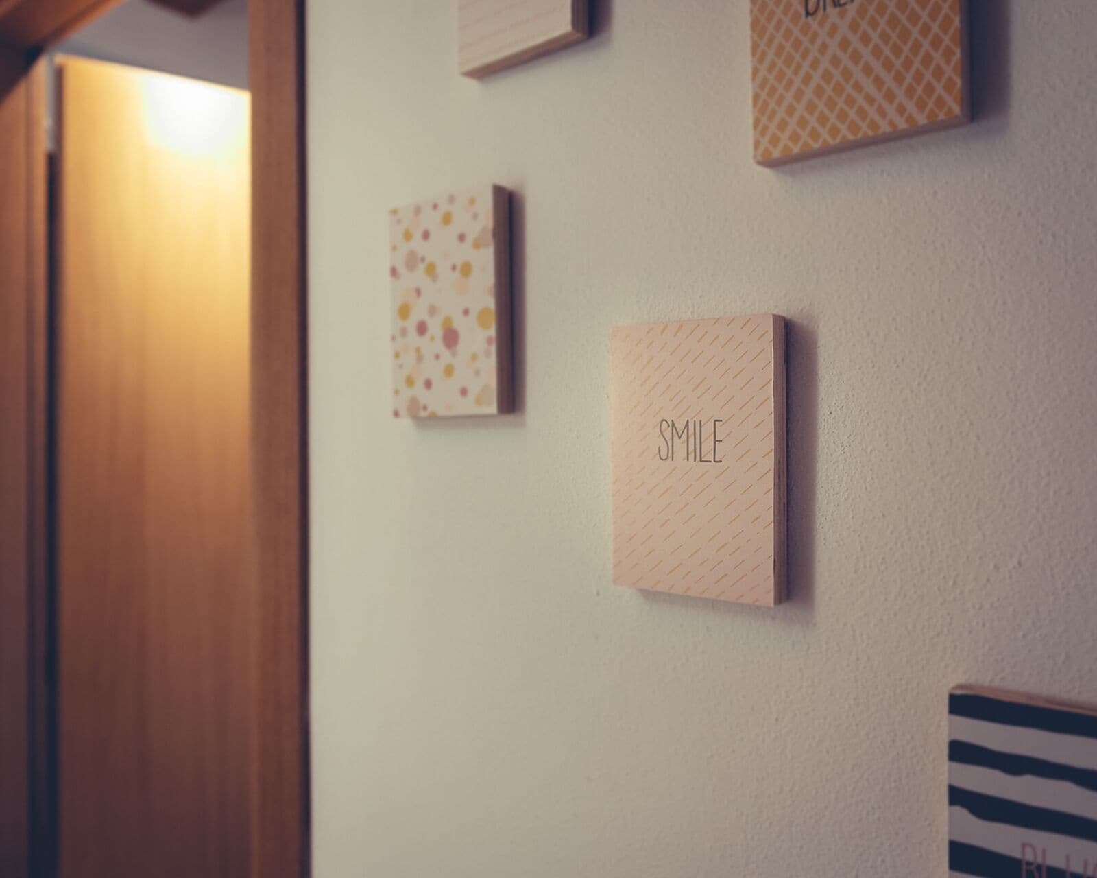 Eine Wand mit mehreren gerahmten Gegenständen, darunter ein gerahmtes Wort 'SMILE' und ein gerahmtes Bild mit einem Punkte-Muster.