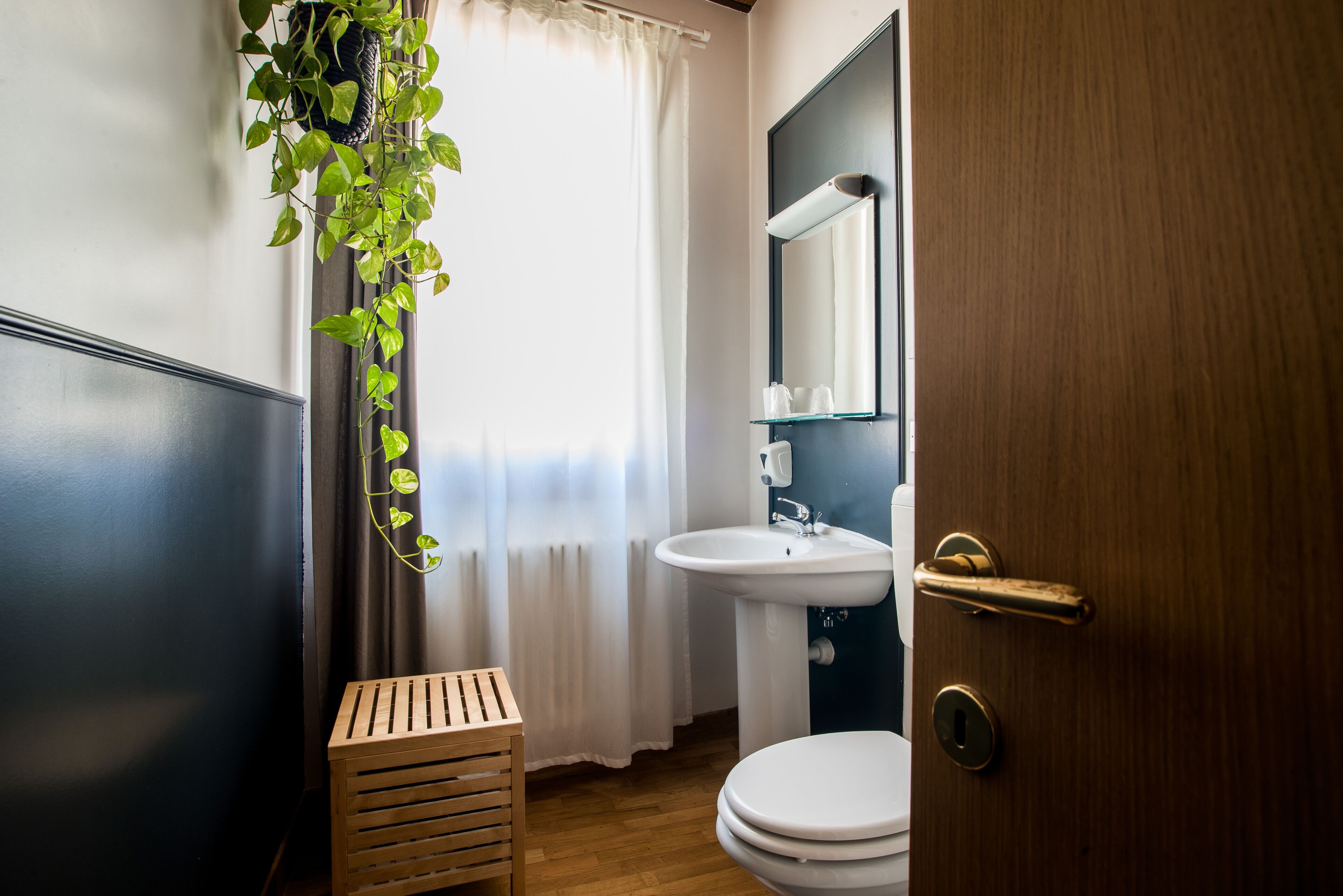 Ein Badezimmer mit Holzschemel, Toilette, Waschbecken und Spiegel.